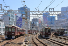 Multiple trains on railway tracks in an urban area, with skyscrapers in the background.