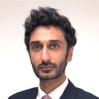 وليد احمد Waleed Ahmed, a man with curly black hair, and the COO of Transreport, facing the camera, wearing a dark suit with a white shirt and purple tie.