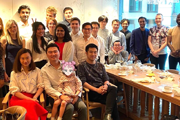 A group photo of some Transreport employees standing and sitting around a table.