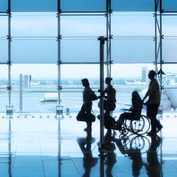 Airport Accessibility Blue-tinted photo of 4 people including a wheelchair user in the airport.