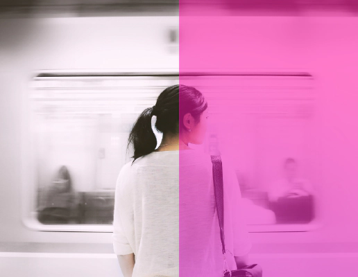 A woman standing on a platform facing a moving train.