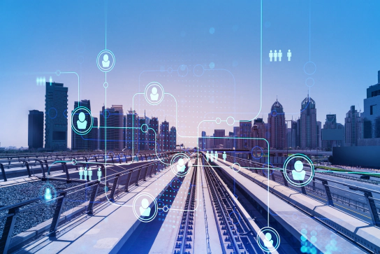 A railway track leading into a city skyline, overlayed with a graphic of an inter-connected matrix of people icons.