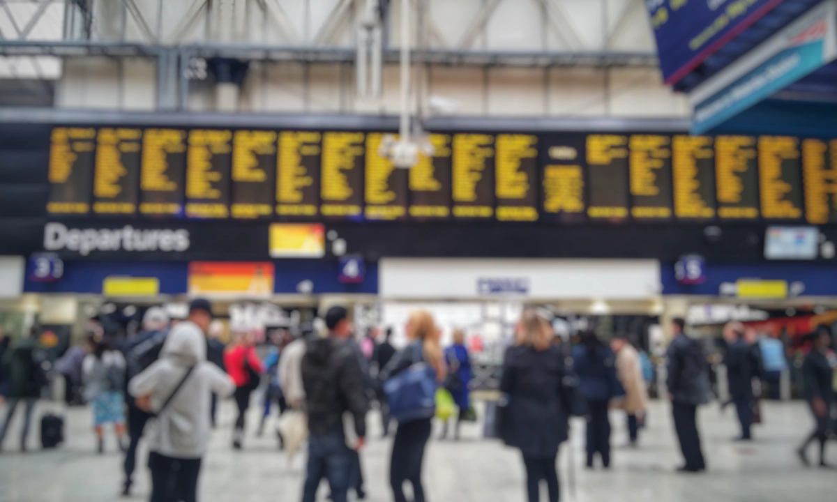 Blurred image of crowded passengers in Waterloo looking at the timetable.