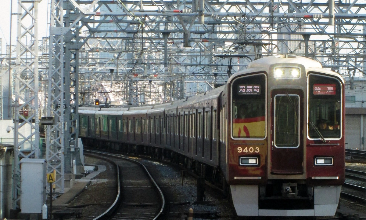 A picture of a dark red Hankyu train on the tracks at Osaka Railway Station.