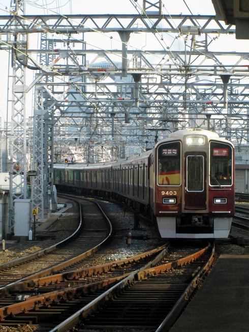 A picture of a dark red Hankyu train on the tracks at Osaka Railway Station.