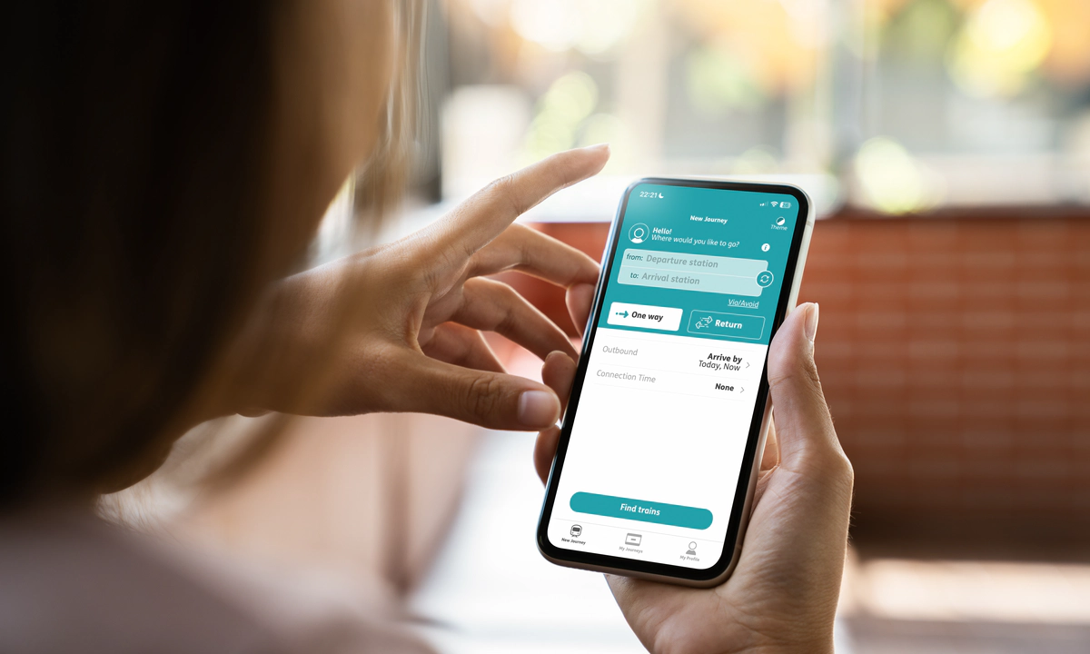 The hands of a woman holding a mobile phone, using the Passenger Assistance app.